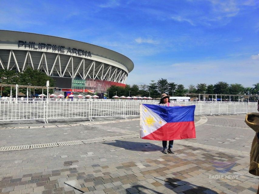  (File photo) A Filipina spectator arriving early at the Philippine Arena, the venue for the historic 30th SEA Games Opening in Ciudad de Victoria, Bocaue, Bulacan, shows her Philippine pride as she poses for a photo with the Philippine flag in front of the 55,000-seater edifice, on Saturday, Nov. 30, 2019. (Photo by Meanne Corvera, Eagle News Service)